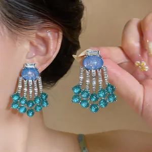 Detail view of retro palace style tassel earrings with blue resin and clear rhinestones