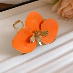 Primo piano di orecchino a fiore in smalto arancione con centro dorato.