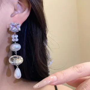 Detail shot of elegant tassel earrings with sparkling rhinestones and white pearls.