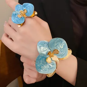 Primo piano di elegante set anello e bracciale con fiori in smalto blu per donne