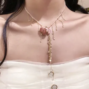 Detail view of a dainty pink rose flower necklace with golden beaded tassels