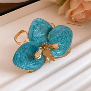 Dettaglio di un orecchino a bottone a forma di fiore in smalto blu e finitura oro