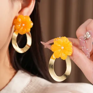Elegant statement earrings featuring orange resin flowers and brushed gold oval hoops