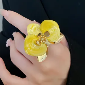 Dettaglio di un orecchino a fiore in smalto giallo vintage con centro in cristallo