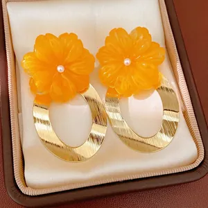 Large orange resin flower earrings with pearl center and golden oval hoop detail