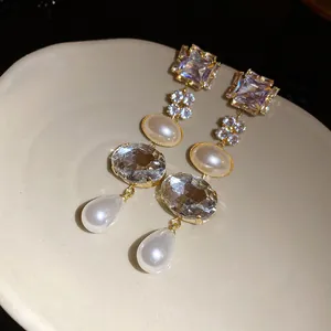 Detailed view of elegant gold-tone dangling earrings with crystals and faux pearls.