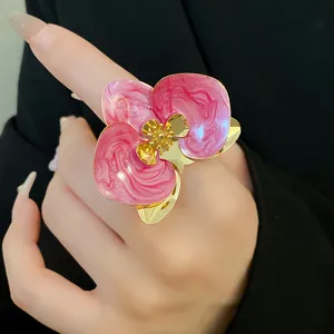 Primo piano di un orecchino a forma di orchidea in smalto rosa con eleganti tocchi d'oro.