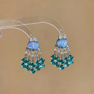 Close-up of vintage palace style earrings with blue resin stones and green tassels