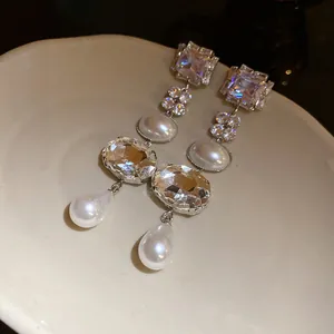 Detailed view of elegant silver crystal and white pearl tassel drop earrings on a plate