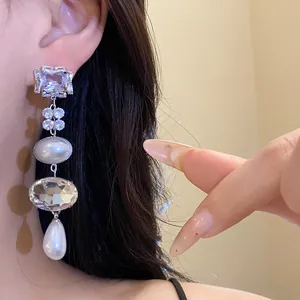 Elegant long silver needle earrings with square crystals and white pearls on a model