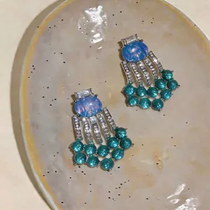 Macro view of vintage court style earrings with blue resin stones and teal beaded tassels