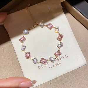 Macro view of gold bracelet with pink and clear cubic zirconia stones on gift pouch