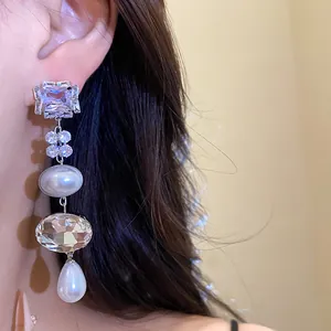 Detail of elegant silver needle earrings featuring faceted crystals and hanging pearls