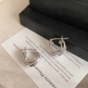 Modern silver double-layer hoop earrings with a cross design on a stylish display.