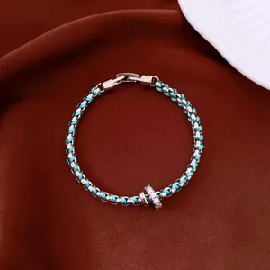 Close-up of a lake blue woven bracelet with silver links and a sparkling crystal ring detail