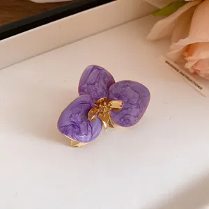 Primo piano di un orecchino vintage a fiore in smalto viola con centro dorato.