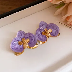 Primo piano di orecchini a fiore in smalto marmorizzato viola con finitura oro