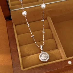 Elegant silver-tone eight-pointed star pendant necklace with pearls in a wooden jewelry box.