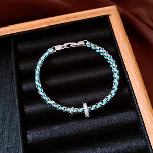 Close-up of turquoise woven bracelet with silver metal chain displayed in black velvet box