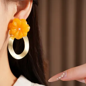 Detailed close-up of a resin flower earring with a brushed gold metal oval hoop