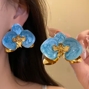 Primo piano dettagliato di orecchini vintage a fiore in smalto blu e oro lucido