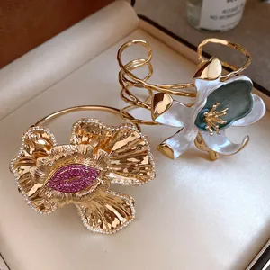 Close-up of vintage gold flower bangles with pink rhinestones and enamel details
