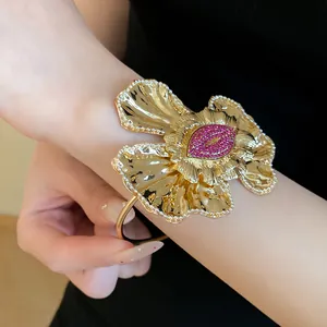 Close-up of gold pleated flower cuff bracelet with pink rhinestone lips.