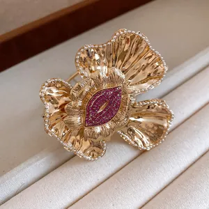 Detailed view of a gold-toned wrinkled flower cuff bracelet with sparkling pink rhinestones.