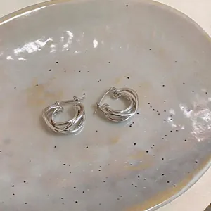 Detailed macro view of silver twisted double-layer hoop earrings on ceramic