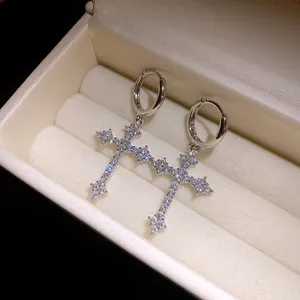 Detailed macro view of elegant sparkling zircon cross pendant huggie hoop earrings