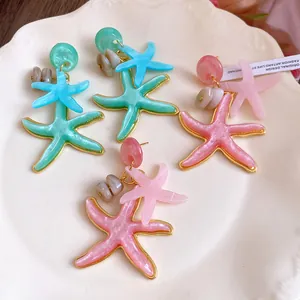 Close-up detail of colorful resin starfish earrings on a white vintage porcelain plate