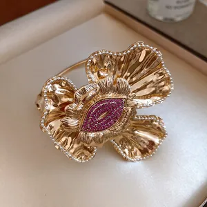 Macro detail of a gold ruffled flower cuff bracelet with pink crystal lip center decoration