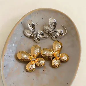 Close-up view of gold and silver butterfly C-shaped earrings with hammered texture