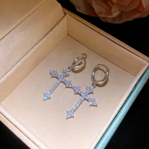 Close-up detail of exquisite sparkling zircon cross hoop earrings presented in a jewelry box.
