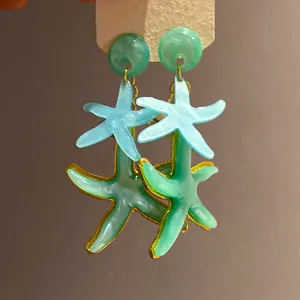 Detailed view of resin starfish drop earrings with blue and green seaside design.