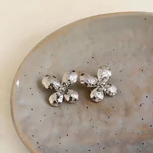 Macro detail of elegant silver-toned butterfly earrings with hammered pleated texture