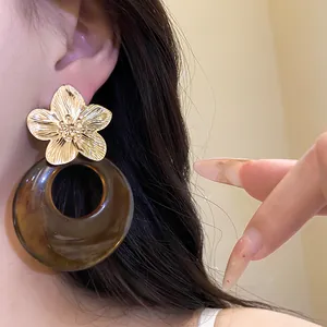 Close-up detail showing texture of vintage golden flower and amber resin hoop earrings