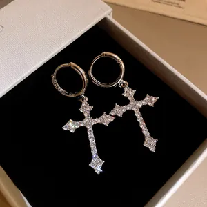 Close-up of sparkling zircon cross pendant hoop earrings in white jewelry box