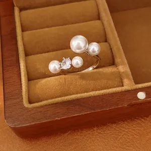 Detail of a silver open ring featuring four white pearls and a brilliant cubic zirconia.