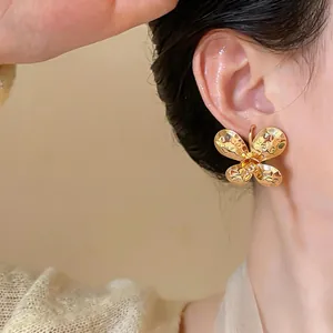 Close-up of gold butterfly stud earrings with textured metallic finish on model