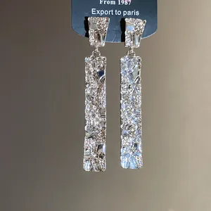 Close-up of silver-toned textured rectangular drop earrings with a crumpled finish