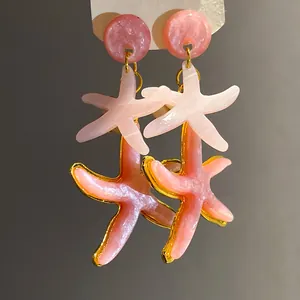 Detailed macro view of pink resin starfish dangle earrings with pearlescent texture