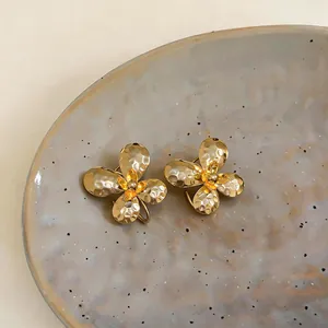 Detailed macro view showing the unique hammered gold texture and floral center of the earrings.