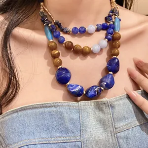 Detail view of a multilayer necklace with blue resin beads and agate stones on a model.