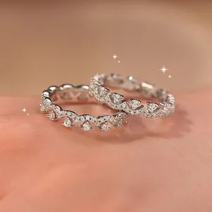 Macro view of two zircon lace rings with sparkling wave design on a soft skin background