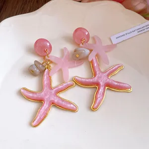 Elegant pink resin starfish dangle earrings with gold edges for vacation style.