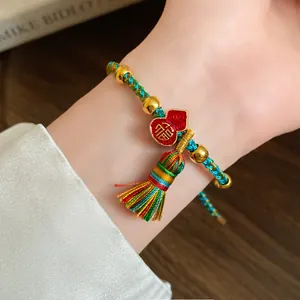 Close-up of handmade woven colorful rope bracelet with gold beads and tassel