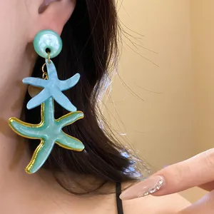 Close-up of double resin starfish drop earrings in blue and green on model