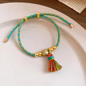 Close-up of hand-woven colorful rope bracelet with clover charm and tassel