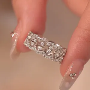 Macro view of exquisite zircon lace-edged ring with sparkling openwork design on a finger.